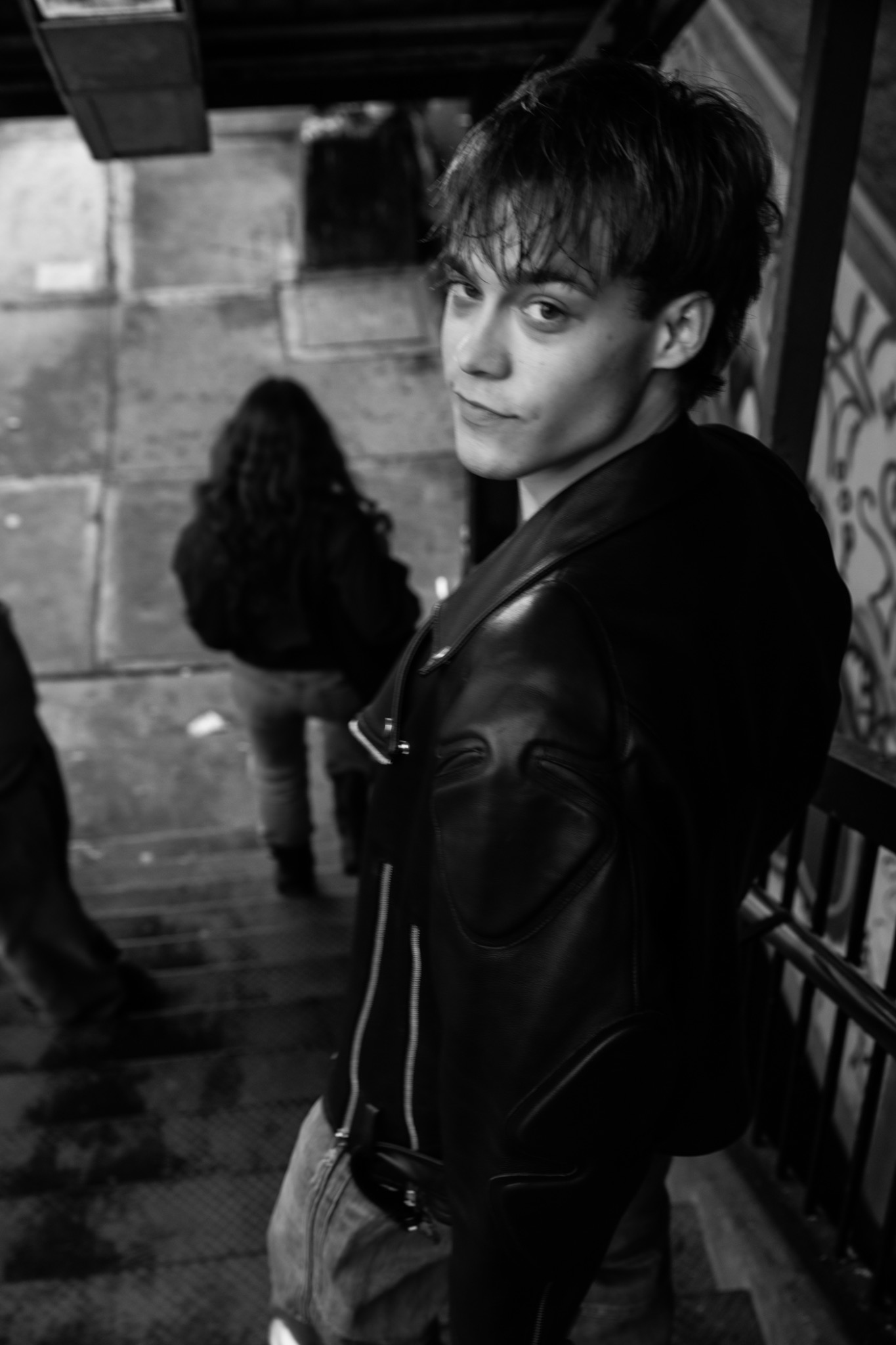 Andrew Ashley looking back in a leather jacket in a black-and-white street portrait